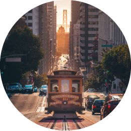 A cable car descends a San Francisco city street at sunset.